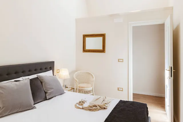 Letto matrimoniale con biancheria bianca e cuscini grigi